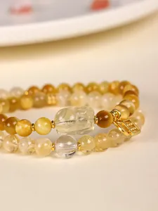 Macro detail of yellow tiger eye and citrine beads with a crystal Pi Xiu charm on bracelet