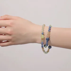 Detail of natural blue and green crystal beaded bracelet worn on a woman's wrist.