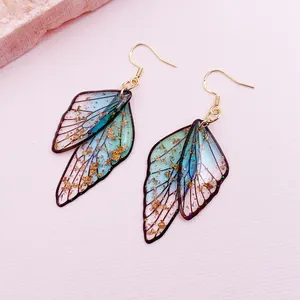 Detail view of cicada wing earrings with gradient blue resin and gold foil flakes