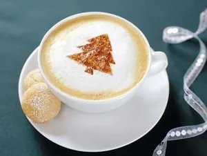 Detail of a Christmas tree latte art on coffee foam using a plastic stencil stencil set.