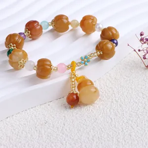Detail eines Jinsiyu-Perlenarmbands mit Kürbisperlen und einem Flaschenkürbis-Anhänger.