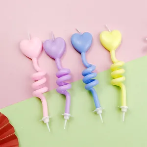 Close-up of four colorful heart-shaped spiral birthday candles for cake decoration.