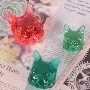 Close-up view of translucent red and green French Bulldog resin heads for DIY crafts