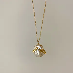 Dettaglio collana con pendente in perla barocca retrò e design a mani che abbracciano.