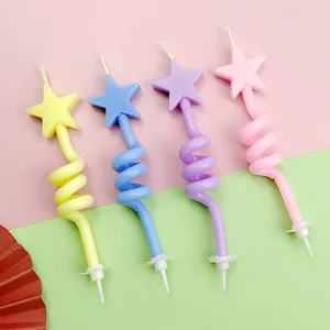 Close-up of four colorful spiral birthday candles with star toppers on a vibrant backdrop