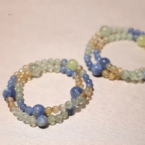 Close-up of handmade natural blue kyanite and crystal beaded bracelets on a textured background.