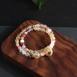 Detail shot of natural red phantom and citrine multi-strand crystal bracelet on wood