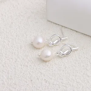 Primo piano macro di eleganti orecchini a nodo in argento con perle d'acqua dolce naturali