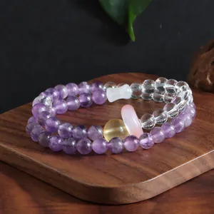 Macro view of natural amethyst and citrine beaded double-loop bracelet on wooden base