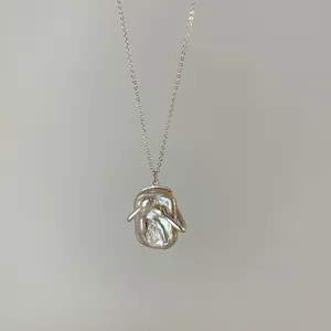 Dettaglio collana con pendente in perla barocca e design a abbraccio in argento