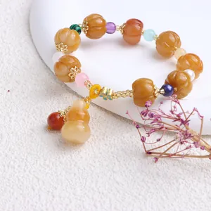 Nahaufnahme eines gelben Jade-Armbands mit geschnitzten Kürbisperlen und Flaschenkürbis