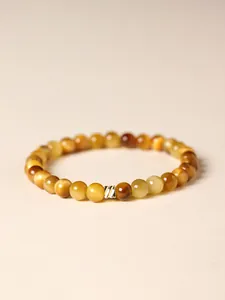 Close-up of golden tiger's eye beaded bracelet with a textured gold-tone metal charm.