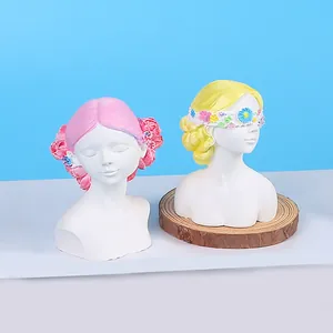 Detailed view of two artistic girl bust statues with floral hair and blindfold decor.