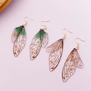 Close-up of handmade gradient cicada wing earrings with gold foil accents