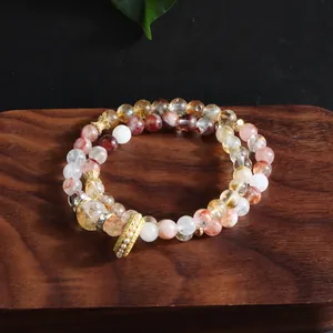 Multi-strand natural mixed crystal bracelet with gold charms on wooden tray display