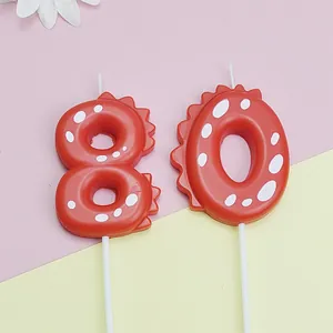 Close-up of red dinosaur-themed number 80 candles for kids birthday cake topper