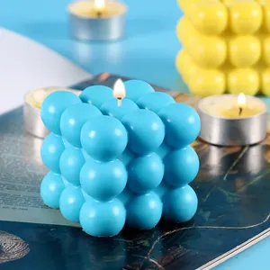 Macro view of a lit blue bubble cube candle placed on a decorative magazine page