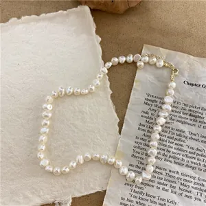 Detailed view of a vintage-style irregular rice pearl necklace on textured paper.