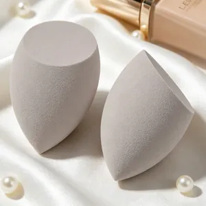Detailed macro view of gray slanted-cut beauty sponges on elegant white silk with pearls