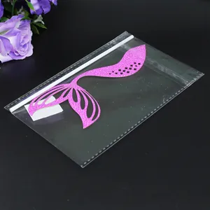 Detailed view of pink glitter mermaid tail cake topper in clear plastic packaging