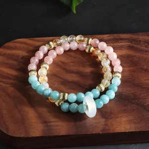 Detail of multi-layered natural crystal bead bracelets with gold accents on a wooden tray