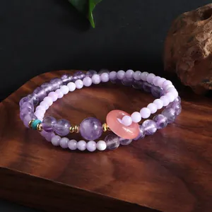 Detailed macro view of double-layer purple amethyst bracelet with pink donut pendant
