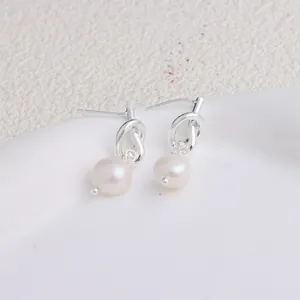 Primo piano dettagliato di orecchini a nodo argento con perle bianche naturali pendenti.