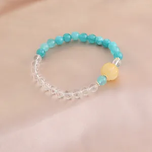 Nahaufnahme eines Naturkristall-Armbands mit blauen Perlen und gelbem Kürbis-Anhänger.