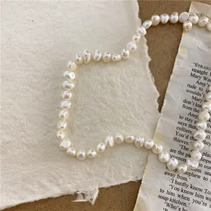 Macro detail of an irregular baroque natural pearl necklace on vintage paper background.