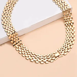 Detail of a wide gold punk style watch-band link necklace on a display block