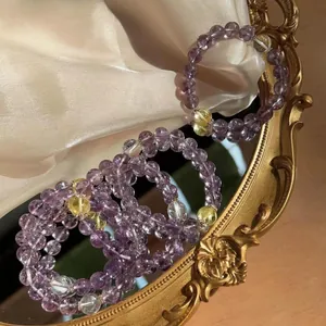 Close-up of purple amethyst and yellow quartz beaded bracelets on vintage mirror