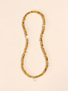 Golden tiger eye beaded necklace with pearl and blue accents on beige background