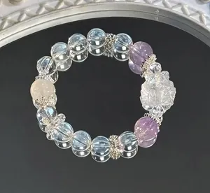 Nahaufnahme eines Naturkristallarmbands mit klaren und lila Perlen und Rose