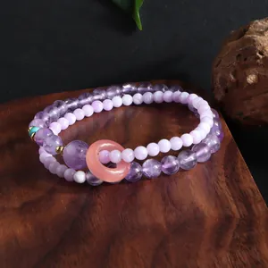 Close-up of a double-layered purple crystal beaded bracelet with a peach ring charm.