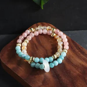 Macro detail of multi-layer natural crystal bracelet with a white donut ring charm