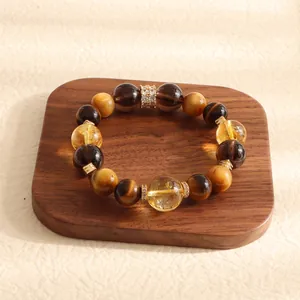 Macro shot of a high-end tiger eye and yellow crystal beaded bracelet on a walnut wood tray