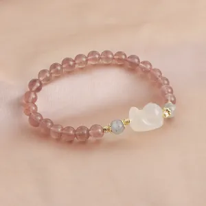 Detailed macro shot of natural strawberry quartz crystal bracelet on silk background.