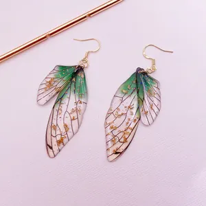 Macro view of translucent green gradient cicada wing earrings with gold foil flakes