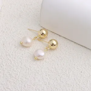 Primo piano di eleganti orecchini a perno dorati con perle naturali d'acqua dolce.
