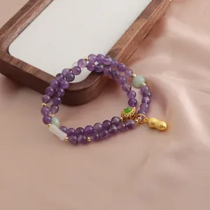 Primo piano di un braccialetto a doppio filo in ametista viola con ciondolo a forma di arachide