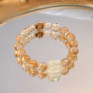 Gros plan d'un bracelet en perles de citrine jaune avec reflet sur un miroir doré.