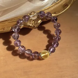Detailed close-up of a natural purple and yellow crystal bead bracelet on wood surface