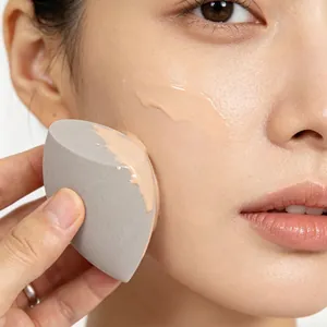 Close-up view of a grey angled beauty blender sponge applying foundation on smooth skin