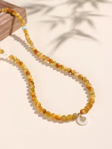 Close-up of yellow tiger eye beaded bracelet with white shell pendant detail
