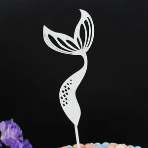 A close-up detail of a silver glitter mermaid tail cake topper for party decor