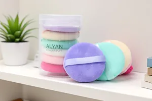 Close-up view of 6 colorful soft makeup powder puffs stored in a transparent cylindrical case