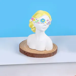 Detailed view of white blindfolded girl gypsum doll with colorful flower accents