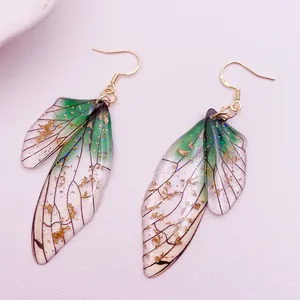 Macro view of translucent green cicada wing earrings with shiny gold foil flakes
