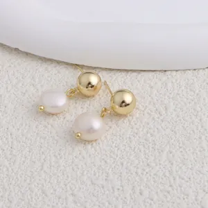 Primo piano di eleganti orecchini pendenti con perle dorate e perle d'acqua dolce bianche