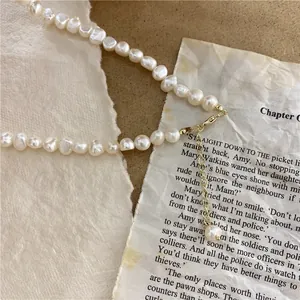 Close-up of natural baroque pearl necklace with adjustable gold clasp.